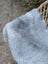 A soft light gray icelandic sheepskin throw draped over a wicker chair showcasing long wool icelandic texture