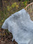 A plush light gray long wool icelandic sheepskin blanket draped over a wicker chair for cozy warmth