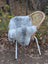 A soft light gray Icelandic sheepskin throw with long wool Icelandic draped over a wicker chair with white metal legs