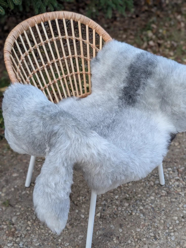 A soft natural grey icelandic sheepskin wool throw draped over a wicker chair showcasing long wool icelandic texture