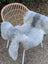 A soft natural grey icelandic sheepskin wool throw draped over a wicker chair showcasing long wool icelandic texture
