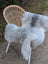 A soft fluffy gray icelandic sheepskin rug with natural mottled texture draped over the back of a wicker chair