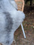 A soft gray wool icelandic sheepskin throw draped over a wicker chair perfect for cozy decor