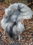 A plush long wool icelandic sheepskin rug in natural grey draped over a chair with woven wooden arms