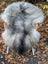 A plush long wool icelandic sheepskin rug in natural grey draped over a wicker chair with white legs