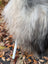 A white cylinder sticks out from the thick shaggy long wool of a natural grey icelandic sheepskin rug