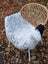 A plush spotted icelandic sheepskin throw blanket in white and black draped over a wicker chair