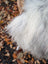 Fluffy white faux fur blanket with soft shaggy texture resembling wool icelandic long wool sheepskin in natural grey