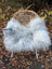 A plush icelandic sheepskin throw in natural grey with long wool draped over a rattan chair with metal legs