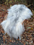 A plush long wool icelandic sheepskin rug in natural grey draped over a wicker chair measuring 53 x 32 inches