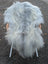 A plush long wool icelandic grey sheepskin rug draped over a chair with woven wicker arms and white metal legs