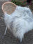 A plush long wool icelandic grey sheepskin throw draped over a wicker chair perfect for cozy living spaces