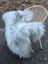 A plush grey icelandic sheepskin throw draped over a wicker chair showcasing long wool icelandic texture
