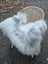 Fluffy white and grey icelandic sheepskin cover draped over wicker chair made of long wool icelandic sheepskins