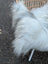 A fluffy white and grey icelandic sheepskin throw draped over a wicker chair showcasing long wool icelandic sheepskins