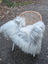 A plush long wool icelandic sheepskin throw in natural grey draped over a woven wicker chair with metal legs