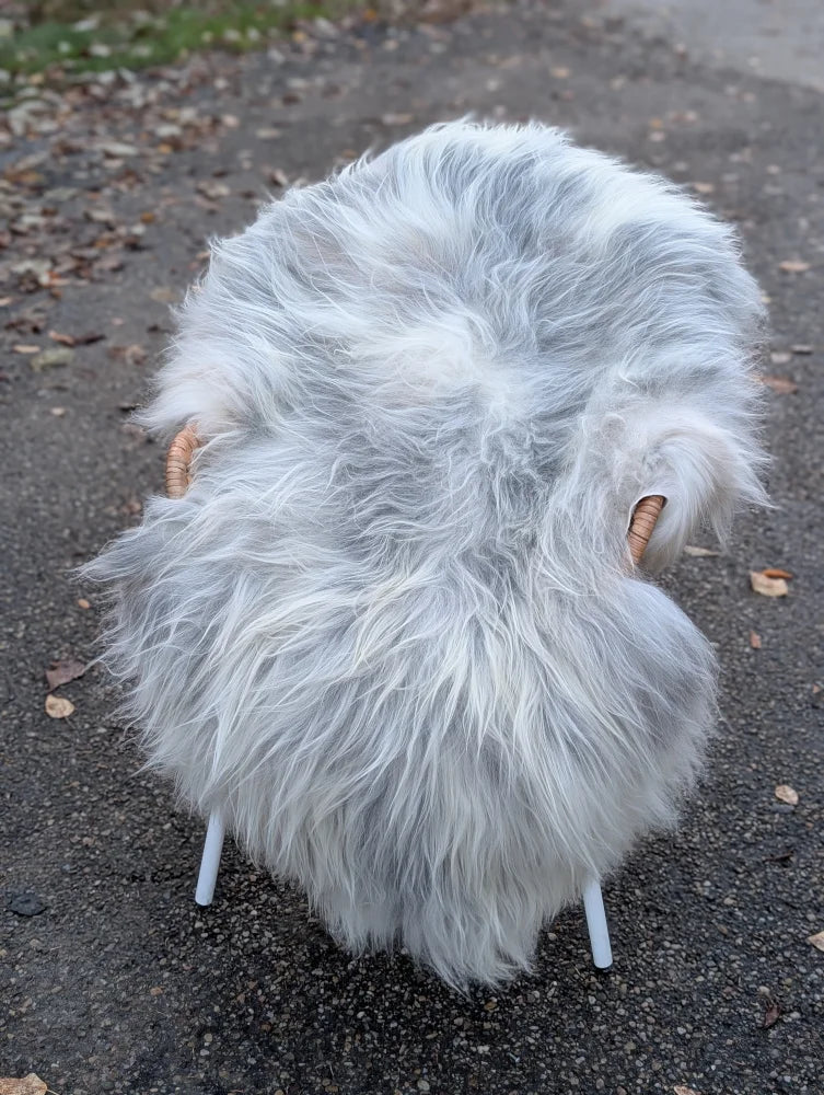 A fluffy light gray ice74 outdoor chair with long wool icelandic sheepskin and wooden horn handles