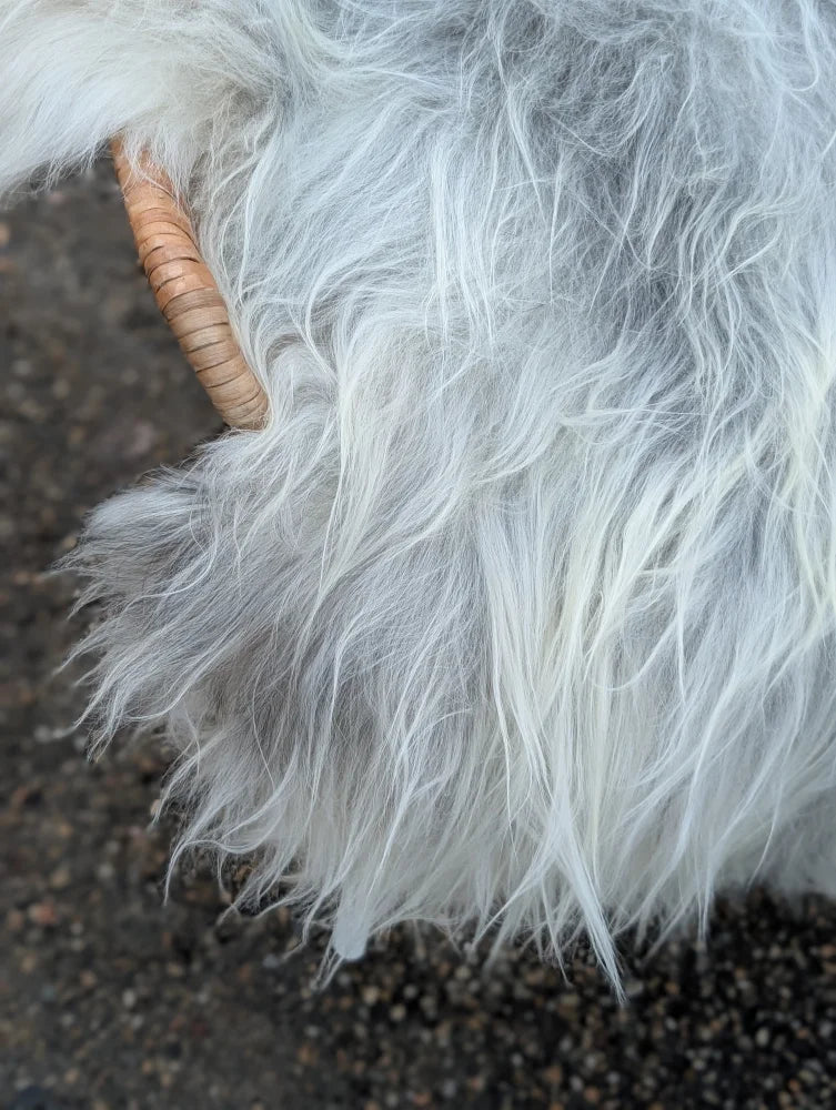 A woven wooden grip handle wrapped in fluffy light grey and white wool icelandic sheepskins faux fur basket