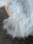 A woven wooden grip handle wrapped in fluffy light grey and white wool icelandic sheepskins faux fur basket