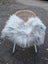 A cozy grey icelandic sheepskin throw made of long wool icelandic material draped over a wicker chair with white legs