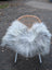 A cozy chair with a woven wicker back and white legs draped in a plush grey icelandic sheepskin throw