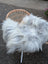 A fluffy grey icelandic sheepskin wool throw draped over a wicker chair with slender metal legs for cozy decor