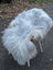 A plush white sheep-shaped chair with wooden horns and slender legs made from long wool Icelandic sheepskins