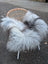 A massive 56 x 35 inch long wool icelandic sheepskin throw in natural grey draped over a wicker chair with white legs