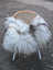 A cozy long wool icelandic grey sheepskin throw draped over a wicker chair with white legs perfect for snuggling