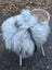 A plush grey icelandic sheepskin wool throw draped over a wicker chair with slender metal legs
