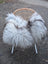 A cozy long wool icelandic grey sheepskin throw draped over a woven wicker chair with white legs