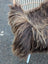 A plush dark rusty icelandic sheepskin throw with long wool draped over a wicker chair for cozy style
