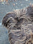 A fluffy dark rusty icelandic sheepskin tail with long wool in dark brown and tan on the back side of the product