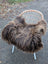 A cozy dark rusty icelandic sheepskin throw with long wool draped over a modern wicker chair with white legs