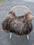 A cozy massive 56 x 35 dark rusty icelandic sheepskin throw with long wool draped over a modern rattan chair
