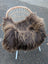 A cozy dark rusty icelandic sheepskin throw with long wool draped over a wicker chair with white metal legs