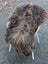 Thick shaggy dark rusty icelandic sheepskin rug with long wool draped over modern chair with light wooden arms