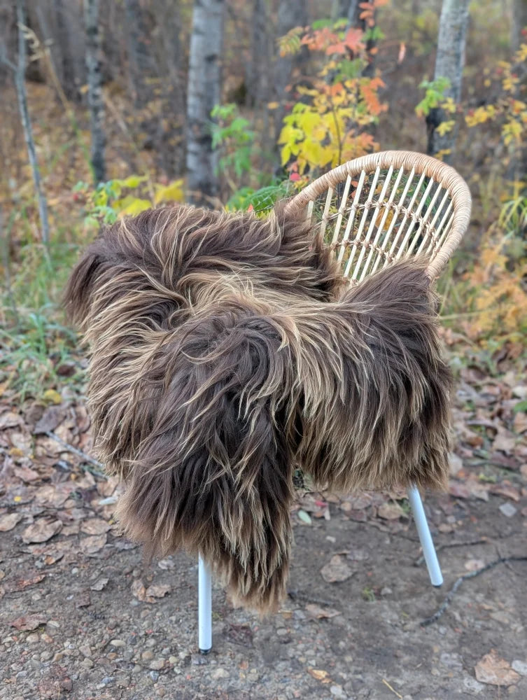 A cozy thick brown faux fur throw draped over a rattan chair featuring massive natural bronze icelandic sheepskin wool
