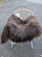 Cozy thick dark rusty icelandic sheepskin throw with long wool draped over white-legged wicker chair