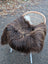 A plush long wool icelandic sheepskin throw in dark rusty icelandic colors draped over a modern wicker chair with white legs