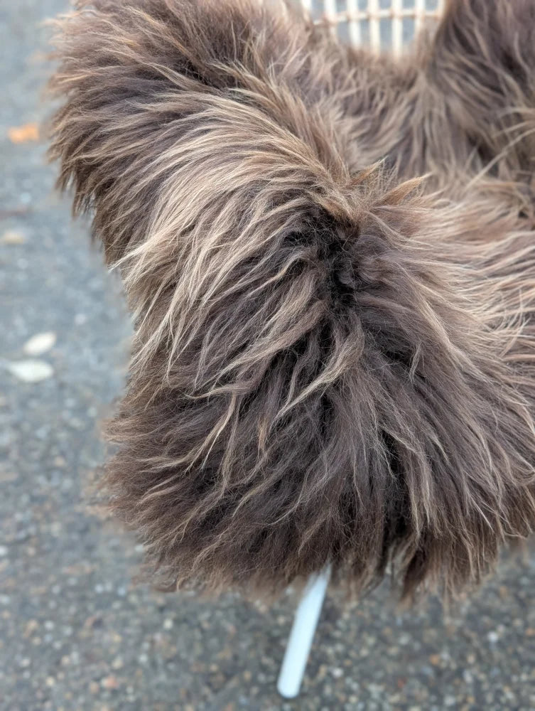 A fluffy long wool icelandic sheepskin coat in dark rusty bronze with soft shaggy texture measuring 58 by 34 inches