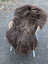 Thick shaggy dark rusty icelandic sheepskin rug draped over woven wicker chair in massive natural bronze color