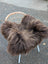 Thick shaggy dark rusty icelandic sheepskin throw draped over woven wicker chair in massive natural bronze color