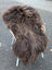 Thick dark rusty icelandic sheepskin with long wool draped over a minimalist chair with white legs and woven handles