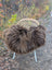 A cozy thick brown wool icelandic sheepskin throw draped over a wicker chair with white metal legs