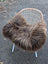 A cozy thick dark rusty icelandic sheepskin throw draped over a modern white wicker chair for extra warmth