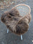 Cozy thick dark rusty icelandic sheepskin rug draped over white wicker chair with slender legs natural long wool icelandic