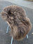 A plush long wool icelandic sheepskin rug in dark rusty bronze draped over a white wicker chair