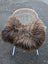 A cozy thick dark rusty icelandic long wool icelandic sheepskin draped over a woven wicker chair with white legs