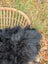 A fluffy black long wool icelandic sheepskin rug resting in a woven wicker basket for cozy home decor